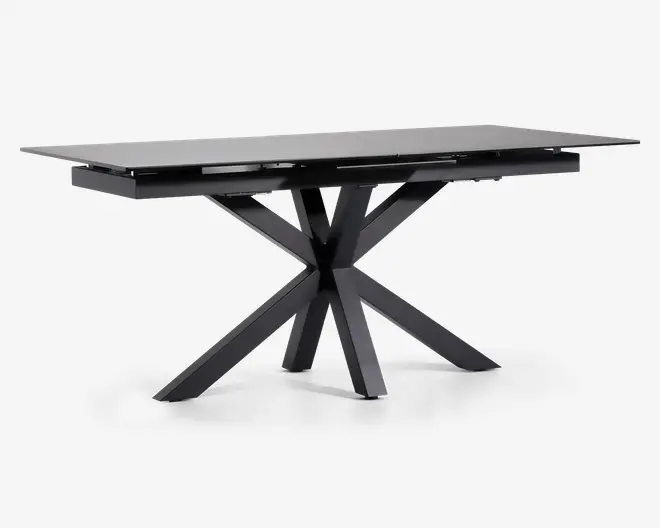 Rektangulært bord med en elegant, mat sort finish. Bordpladen er flad og glat, understøttet af en markant geometrisk base med fire skråtstillede ben, der mødes i midten og giver et moderne, skulpturelt udtryk. Bordet fremstår robust og rummeligt, velegnet til spise- eller arbejdsbrug.