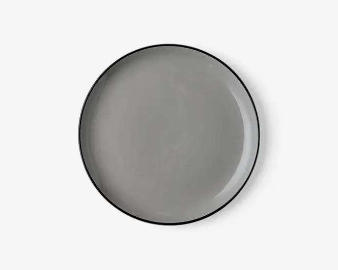 Rund tallerken med en glat, blank lysegrå overflade og en tynd, let hævet kant. Tallerkenens kant er diskret mørkere, hvilket giver et minimalistisk og moderne udtryk. Tallerkenen ser ud til at være lavet af keramik eller porcelæn.