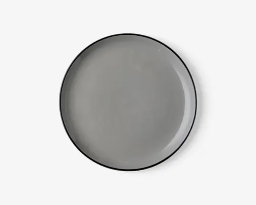Rund tallerken med en glat, blank lysegrå overflade og en tynd, let hævet kant. Tallerkenens kant er diskret mørkere, hvilket giver et minimalistisk og moderne udtryk. Tallerkenen ser ud til at være lavet af keramik eller porcelæn.