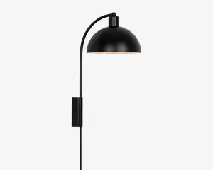 En moderne væglampe med mat sort finish. Lampen har en kuppelformet skærm og en buet arm, der strækker sig ud fra et lodret vægbeslag. Designet er minimalistisk med rene linjer og en glat overflade, hvilket gør den velegnet til moderne indretning. Lyset rettes nedad og giver fokuseret belysning.