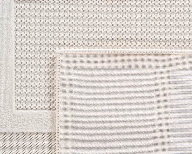 Nærbillede af to overlappende rektangulære tekstiler i en neutral cremefarve. Det øverste tekstil har et fint, tæt vævet mønster med diskrete horisontale linjer og en pænt afsluttet kant. Det nederste tekstil viser et mere tekstureret, kurvevævet mønster med en bred kant. Begge tekstiler har et blødt, elegant udseende og fremhæver forskellige væveteknikker.
