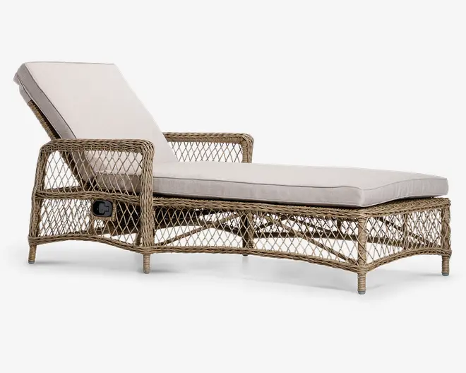 En udendørs liggestol med justerbar ryglæn, fremstillet af flettet rattan med en naturlig finish. Stolen har en tyk, lysebeige hynde på både sædet og ryglænet for ekstra komfort. Armlænene er også lavet af rattan, og der er en synlig håndtag på siden til at justere ryglænets vinkel. Basen er hævet på korte, robuste ben, og det åbne fletdesign giver et luftigt og stilfuldt udtryk.