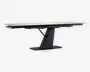 Rektangulært bord med en lys, glat bordplade og en moderne, vinklet sort sokkel. Soklen har et geometrisk design med en bred, flad bund for stabilitet og en central støtte, der vinkler opad for at møde bordpladen. Bordet ser ud til at have en udtræksmekanisme, som giver mulighed for ekstra siddepladser eller større overflade.