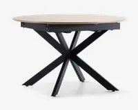 Et rundt bord med en lys træbordplade og en moderne, sort metalbase med fire skråtstillede ben, der krydser hinanden i midten og danner en stabil og stilfuld understøtning. Bordpladen har en glat overflade og let skrå kanter.
