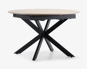 Et rundt bord med en lys træbordplade og en moderne, sort metalbase med fire skråtstillede ben, der krydser hinanden i midten og danner en stabil og stilfuld understøtning. Bordpladen har en glat overflade og let skrå kanter.