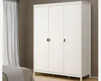 Et moderne, fritstående garderobeskab med et rent og minimalistisk design. Skabet har tre høje låger med enkle brune greb, en glat hvid overflade og står på korte ben. Det har en flad top og diskrete paneldetaljer langs kanterne, hvilket giver et stilrent og nutidigt udtryk.