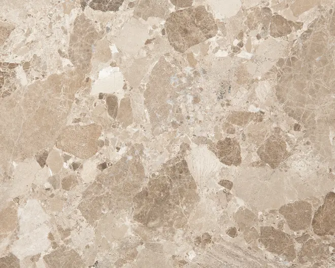 Overflade med et naturstensmønster i lyse og mellembrune nuancer, blandet med beige og cremefarvede felter. Teksturen viser uregelmæssige, organiske former og diskrete årer, hvilket giver et realistisk og jordnært udtryk. Finishen virker glat og let blank, velegnet til gulve eller bordplader.