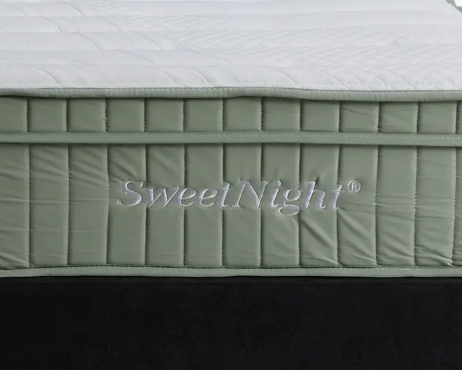 Nærbillede af en madras sidepanel med quiltet, lysegrønt stof og lodrette syninger samt mærkenavnet 'SweetNight' broderet med hvid tråd. Toppen er hvid med et diskret, syet mønster, der giver ekstra struktur og komfort.