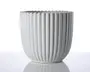En hvid keramisk beholder med lodrette riller og bølget kant. Overfladen er blank, og formen er cylindrisk med en let afrundet bund. Designet er moderne og minimalistisk, velegnet til dekorative formål.