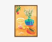 Farverigt indrammet kunstværk med varm gul-orange baggrund, der viser en blågrøn vase med hvide margueritter, et cocktailglas med blomster, citrusfrugt og en skåret papaya.