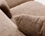 Nærbillede af en beige, kraftigt ტექstureret polstret overflade med bløde, afrundede puder og synlige sømdetaljer.