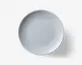 Rund, hvid tallerken med et diskret, tekstureret mønster af lodrette linjer, der stråler ud fra kanten mod midten. Overfladen er glat og blank, hvilket giver et rent og moderne udtryk. Designet er minimalistisk og egner sig til både hverdags- og festlige borddækninger.