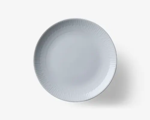 Rund, hvid tallerken med et diskret, tekstureret mønster af lodrette linjer, der stråler ud fra kanten mod midten. Overfladen er glat og blank, hvilket giver et rent og moderne udtryk. Designet er minimalistisk og egner sig til både hverdags- og festlige borddækninger.
