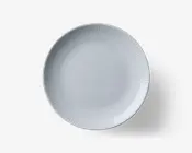 Rund, hvid tallerken med et diskret, tekstureret mønster af lodrette linjer, der stråler ud fra kanten mod midten. Overfladen er glat og blank, hvilket giver et rent og moderne udtryk. Designet er minimalistisk og egner sig til både hverdags- og festlige borddækninger.