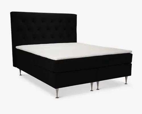 Moderne seng med høj, polstret sengegavl i sort stof med knapdetaljer. Sengen har en tyk, hvid topmadras og står på seks slanke, metalben, der giver et moderne udtryk. Designet er minimalistisk og elegant, velegnet til et stilfuldt soveværelse.