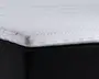 Nærbillede af et madras-hjørne, der viser en hvid, quiltet og tekstureret overflade med et tykt, polstret lag. Syningen er synlig langs kanten, og madrassen ligger oven på en sort stofbetrukket bund. Overfladen ser blød og polstret ud, hvilket indikerer komfort og støtte.