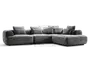 Stor grå hjørnesofa med lav profil, afrundede armlæn og flere løse ryghynder; chaiselong på højre side.