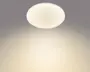 Rund loftlampe til plan montering med hvid kant og blødt varmt lys, vist tændt mod et gråt loft.