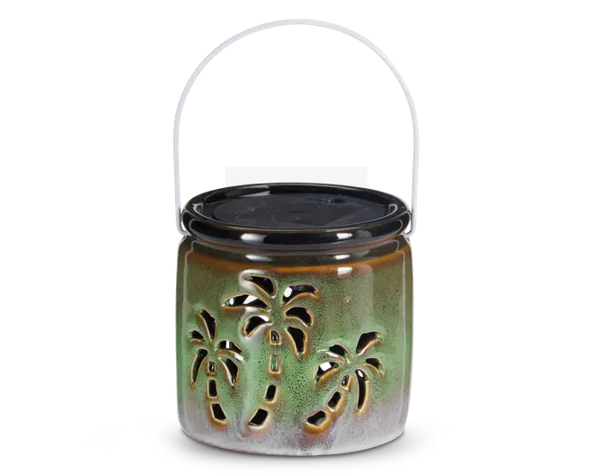 Keramisk lanterne med blank grøn og brun farvegradient, dekoreret med udskårne palmetræsmotiver på siderne, så lyset kan skinne igennem. Lanternen har et aftageligt sort låg og et metalhåndtag til nem transport eller ophængning.