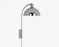 Væghængt lampe med blank kromfinish, buet arm og halvkugleformet skærm. Lampen har et stilrent, moderne design med en rektangulær vægplade og en synlig ledning, der går nedad. Den reflekterende overflade på skærmen giver et moderne udtryk.