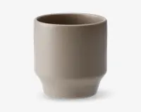 En minimalistisk, cylindrisk kop med mat taupe-finish. Koppen har lige sider, der let smalner ind mod bunden og danner en diskret fod. Randen er glat og let afrundet, og overfladen er uden dekoration, hvilket giver et moderne og enkelt udtryk.