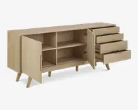 Skænk i lyst træ med skrå ben, to låger til venstre der åbner op til to rummelige hylder, og tre skuffer til højre med indbyggede greb. Designet er minimalistisk og moderne med glatte overflader og rene linjer.