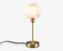 En moderne bordlampe med en cylindrisk fod og stang i messing med mat finish. Lampen har en konisk, halvgennemsigtig hvid lampeskærm, der giver et blødt og diffust lys. Strømledningen går ud fra lampens fod, og det samlede design er stilrent og minimalistisk, velegnet til moderne indretning.