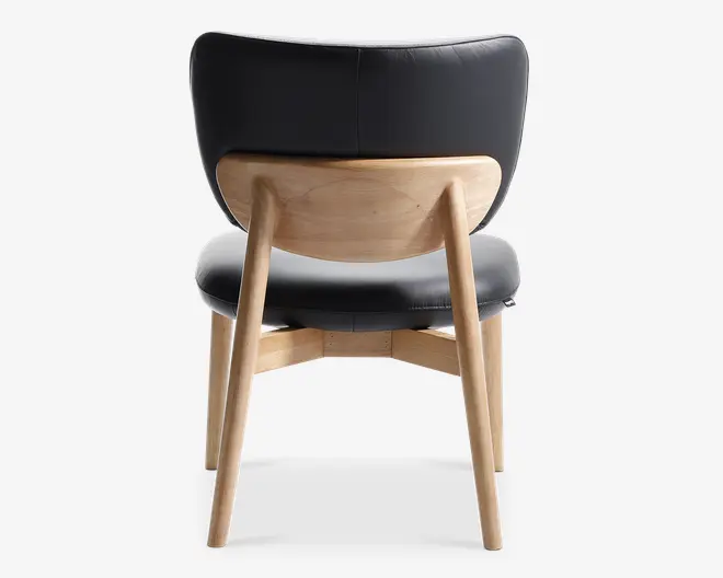 Stol med buet, polstret sort ryglæn og sæde, understøttet af en ramme i lyst træ. Bagsiden af stolen har en glat, naturlig træplade og skråtstillede træben, hvilket giver et moderne og solidt udtryk.
