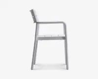 Sideprofil af en stol med minimalistisk design, lige ryglæn, flad sæde med slidser til dræning og integrerede armlæn. Stolen er fremstillet i ét materiale, sandsynligvis metal eller plastik, og har en glat, mat overflade. Benene er let skråtstillede for stabilitet.