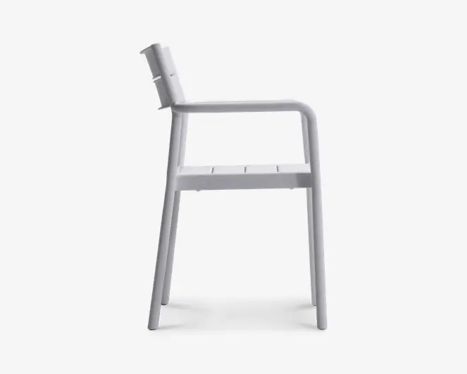 Sideprofil af en stol med minimalistisk design, lige ryglæn, flad sæde med slidser til dræning og integrerede armlæn. Stolen er fremstillet i ét materiale, sandsynligvis metal eller plastik, og har en glat, mat overflade. Benene er let skråtstillede for stabilitet.