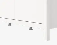 Nærbillede af den nederste del af et hvidt skab med glatte, flade paneler og et minimalistisk design. Skabet står på justerbare grå plastikben, som delvist kan ses under soklen. Overfladen er mat, og kanterne er lige og rene, hvilket giver et moderne udtryk.