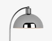 Nærbillede af en moderne lampe med blank kromfinish. Lampen har en kuppelformet skærm og en buet arm, hvilket giver et stilrent og moderne udtryk. Den reflekterende overflade på skærmen tilføjer et elegant præg, og den åbne bund giver direkte lys nedad.