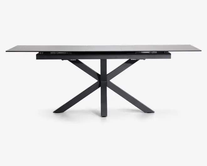 Rektangulært bord med en elegant, mat sort finish. Bordpladen ser ud til at være lavet af et solidt materiale og understøttes af et karakteristisk krydset benstel, som giver både stabilitet og et moderne udtryk. Bordet har rene linjer og et minimalistisk design, der passer til moderne indretning.