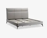 Moderne sengeramme med et lysegråt polstret hovedgærde, der har tre store rektangulære paneler. Rammen har en lav profil med matchende gråt stof på sider og fodende. Sengen har jævnt fordelte lameller i træ til madrasstøtte og står på slanke, skrå sorte ben.