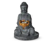 En dekorativ statue med en siddende figur i meditativ stilling, fremstillet af gråt materiale med stentekstur. Figuren holder en gylden lotusformet skål i skødet, som indeholder en cirkulær række af små LED-lys. Statuen har detaljerede folder i kappen og en rund base for stabilitet. Figurens ansigt er bevidst sløret.