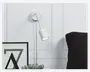 En moderne vægmonteret lampe med en hvid cylindrisk lampeskærm og en fleksibel, justerbar hals, der gør det muligt at rette lyset. Lampen har en rund base og en synlig ledning, der hænger ned. Designet er minimalistisk og velegnet til læsning eller stemningsbelysning.