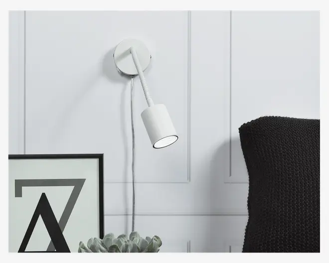 En moderne vægmonteret lampe med en hvid cylindrisk lampeskærm og en fleksibel, justerbar hals, der gør det muligt at rette lyset. Lampen har en rund base og en synlig ledning, der hænger ned. Designet er minimalistisk og velegnet til læsning eller stemningsbelysning.