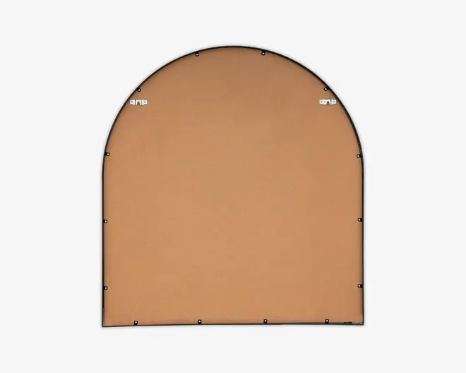 Billedet viser bagsiden af et buet objekt med en glat, lysebrun overflade, sandsynligvis lavet af MDF eller pap. Der er en sort kant rundt om kanten og flere små sorte beslag, der fastgør bagstykket. To metalophæng er placeret nær toppen til vægmontering.