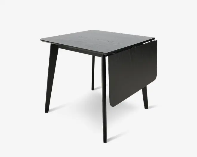 Sort kvadratisk bord med flad bordplade, slanke skrå ben og en nedklappet sideplade, der giver et kompakt, sammenklappeligt udtryk.