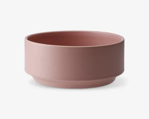 En rund skål med mat finish i en afdæmpet rosa farve. Skålen har lige sider og en let forhøjet bund, hvilket giver et moderne og minimalistisk udtryk. Overfladen er glat og uden mønstre eller tekstur.