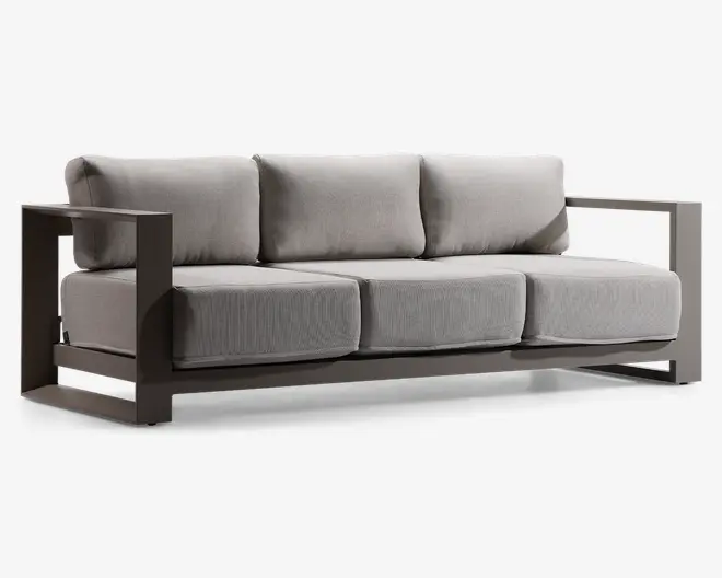 Moderne tresæders med tykke, lysegrå sæde- og ryghynder. Stellet er lavet af robust, mørkfarvet metal med brede, rektangulære armlæn og et åbent, geometrisk design. Hynderne har et blødt, tekstureret stof, og det samlede udtryk er minimalistisk og nutidigt.