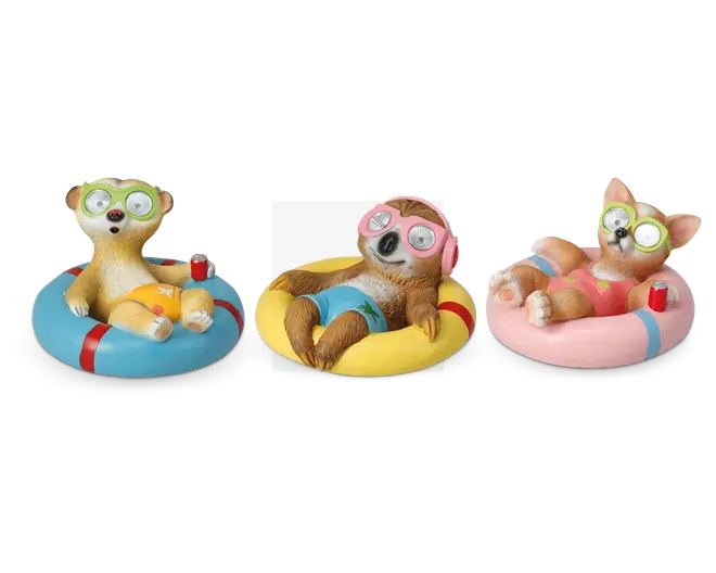 Tre dyrefigurer ligger afslappet på farverige baderinge. Hver figur har badebukser på og grønne briller med agurkeskiver over øjnene, hvilket giver et spa- eller afslapningstema. Den venstre figur ligner et surikat på en blå og rød badering, iført gule badebukser og holder en rød sodavandsdåse. Den midterste figur, delvist skjult af et sløret ansigt, ser ud til at være en dovendyr på en gul badering, iført blå badebukser og lyserøde hovedtelefoner. Den højre figur ligner en corgi-hund på en lyserød og blå badering, iført lyserøde badebukser og holder også en rød sodavandsdåse. Alle figurer har en afslappet og legende positur.