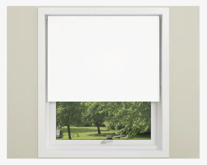En hvid rullegardin dækker delvist et vindue, så den nederste del af vinduet forbliver fri. Gardinet har en glat, ensartet overflade uden synlige mønstre eller teksturer, og vinduesrammen er hvid. Gardinet ser ud til at være lavet af et lystæt materiale, der giver privatliv og lyskontrol.