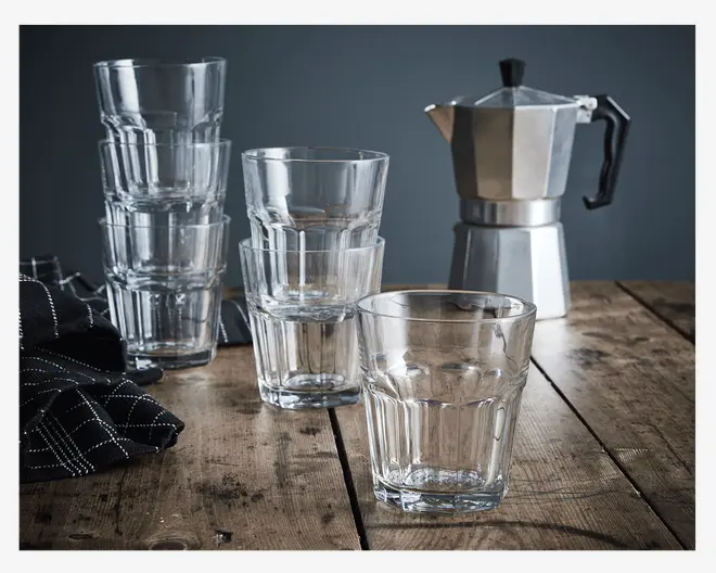 Klar, lave drikkeglas med facetslebet design og tyk, solid bund. Glassene kan stables, hvilket vises ved flere stablede glas. De har et enkelt, moderne udseende og er lavet af gennemsigtigt glas.