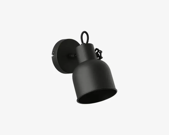 Væghængt lampe i mat sort med en rund, klokkeformet metalskærm. Lampen har en cirkulær base og et justerbart arm, så lysets retning kan ændres. Designet er minimalistisk og moderne, hvilket gør den velegnet til forskellige indretninger.