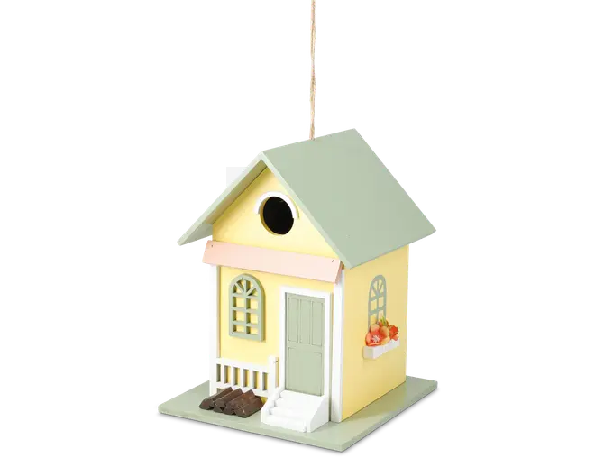 Dekorativt fuglehus formet som et lille gult hus med lysegrønt tag, der har en lille veranda med hvidt gelænder, grøn dør og buede vinduer. Der er en lille hvid trappe op til døren, en blomsterkasse med orange blomster under et vindue, og et rundt indgangshul over verandaen.