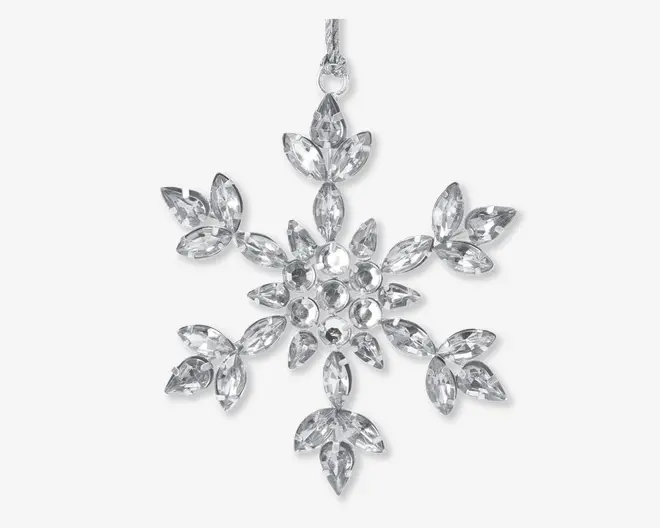Klare, facetslebne krystaller arrangeret i et symmetrisk snefnugmønster med seks spidser. Hver spids har marquise-formede krystaller, der udgår fra en central klynge af runde krystaller. Ornamentet har en sølvfarvet ophængsløkke øverst for nem fastgørelse. Krystallerne reflekterer lyset og giver et funklende, elegant udtryk.