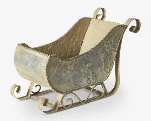 Dekorativ beholder formet som en slæde, fremstillet af metal med antik, patineret finish. Siderne har prægede blomster-mønstre og udsmykkede krøllede detaljer, mens bunden har buede meder og indviklede metaludsmykninger. Farven er en blanding af creme og dæmpet grå, hvilket giver et vintage udseende.