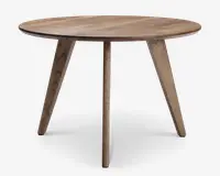 Rundt bord i træ med en glat, naturlig finish. Har tre skråtstillede ben for stabilitet og et minimalistisk, moderne design. Træets årer er synlige og giver et rustikt præg.