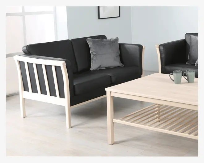 En moderne to-personers sofa med en lys træramme og sorte hynder. Ryggen og siderne har lodrette trælameller, og sædet består af to bløde sædehynder og to ryghynder. Der ligger en blød grå pyntepude på sofaen. Designet er minimalistisk og moderne med rene linjer og neutrale farver.